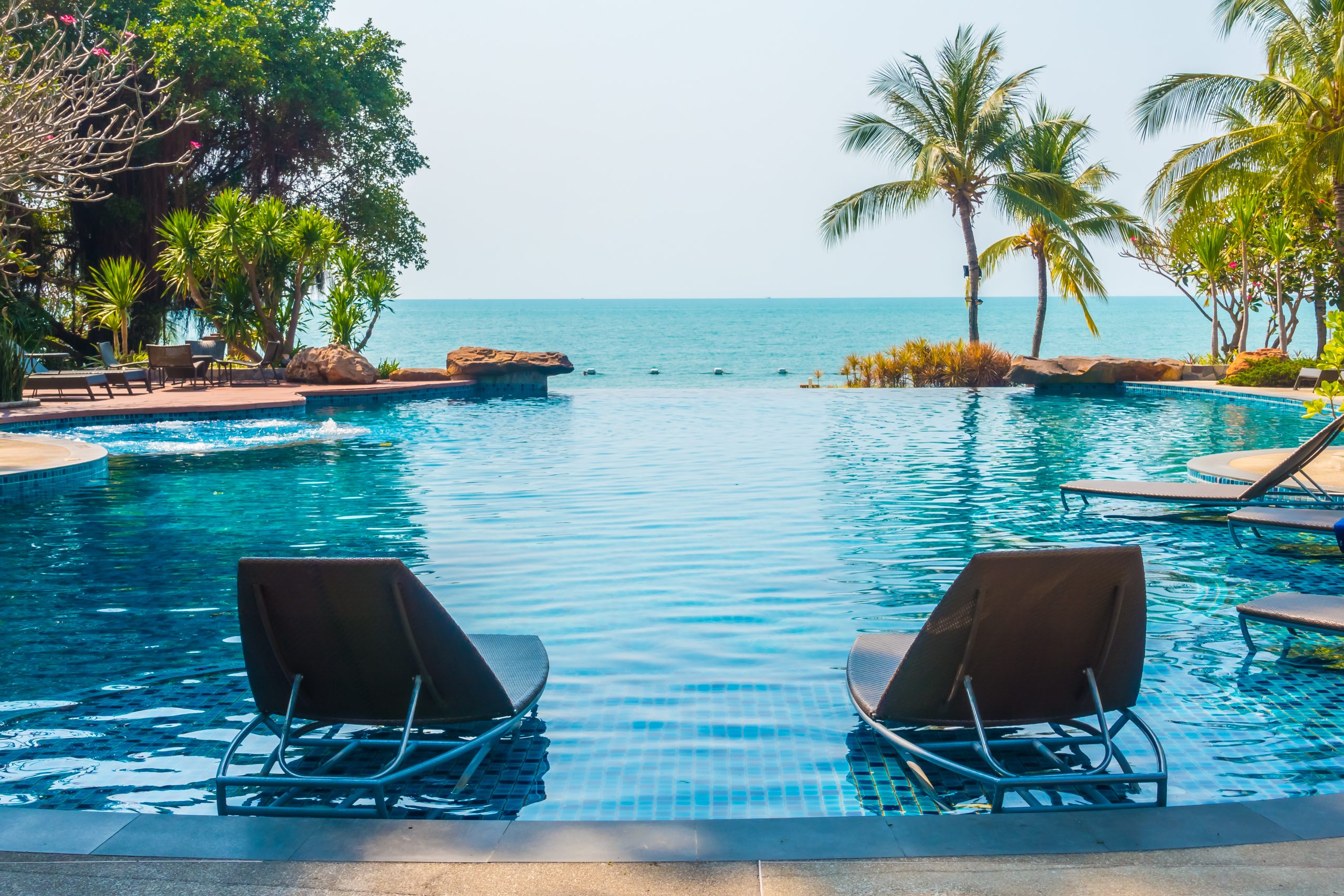 Beautiful luxury Swimming pool with palm tree and sea background in hotel pool resort - Boost up color Processing